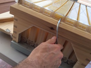 From the rear the beekeeper removes a plastic cap and inserts a (supplied) crank to individually manipulate the desired frame for harvest.