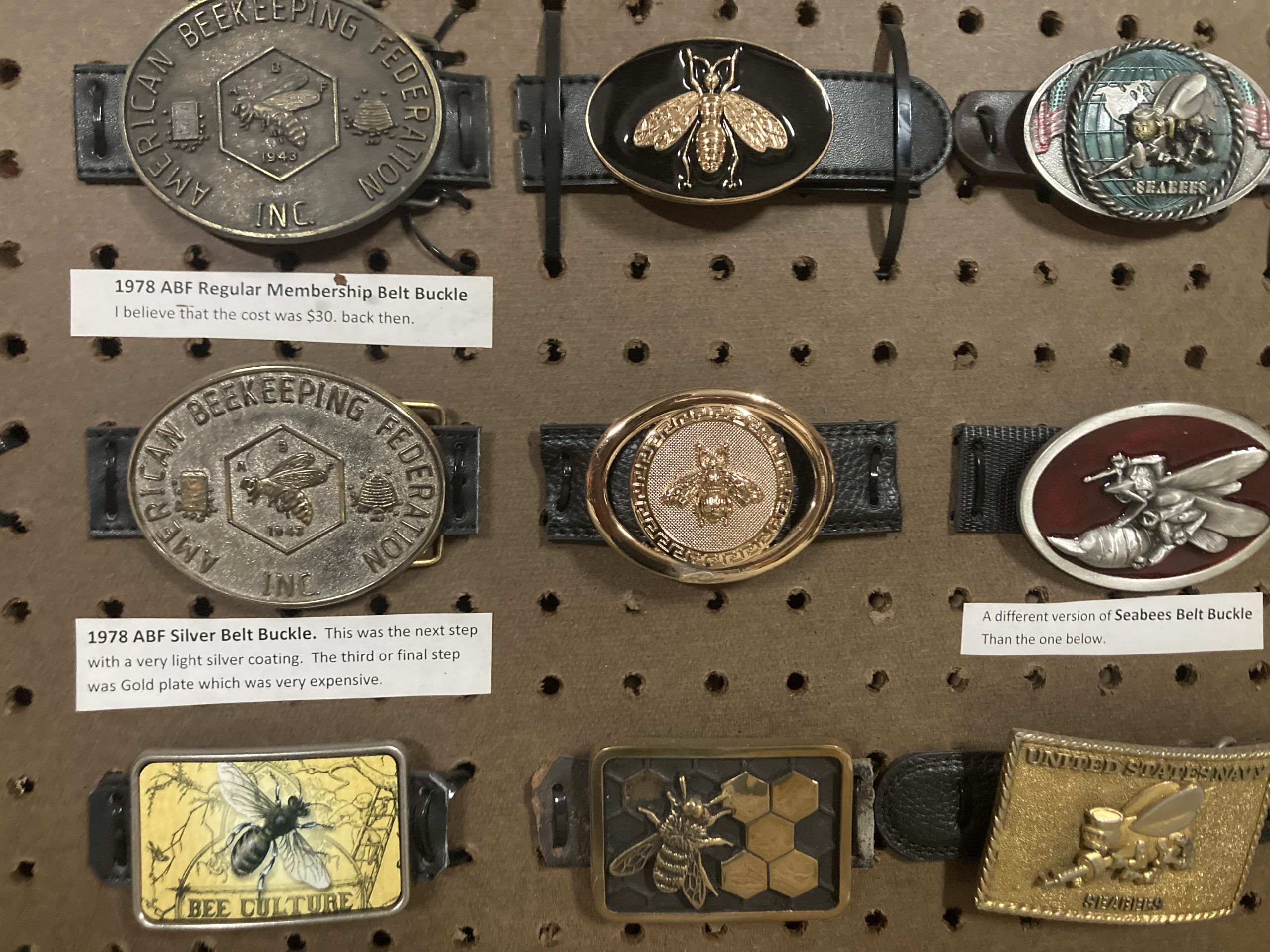 An example of three boards containing belt buckles related to honey bees and beekeeping.